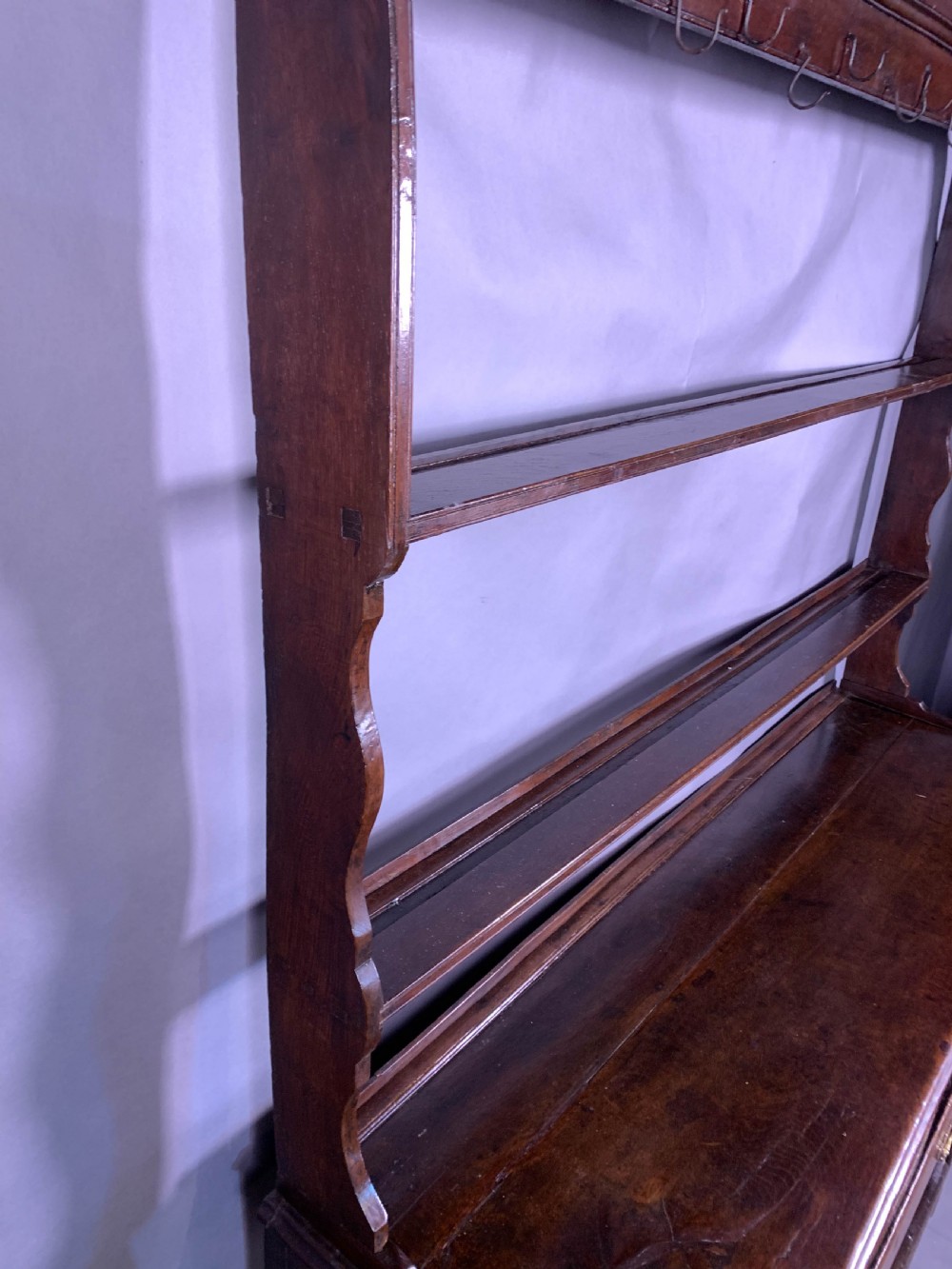 An 18th-century oak Welsh dresser featuring an open rack top with plate hooks, a central base with multiple drawers, and a lower pot board shelf. View XII