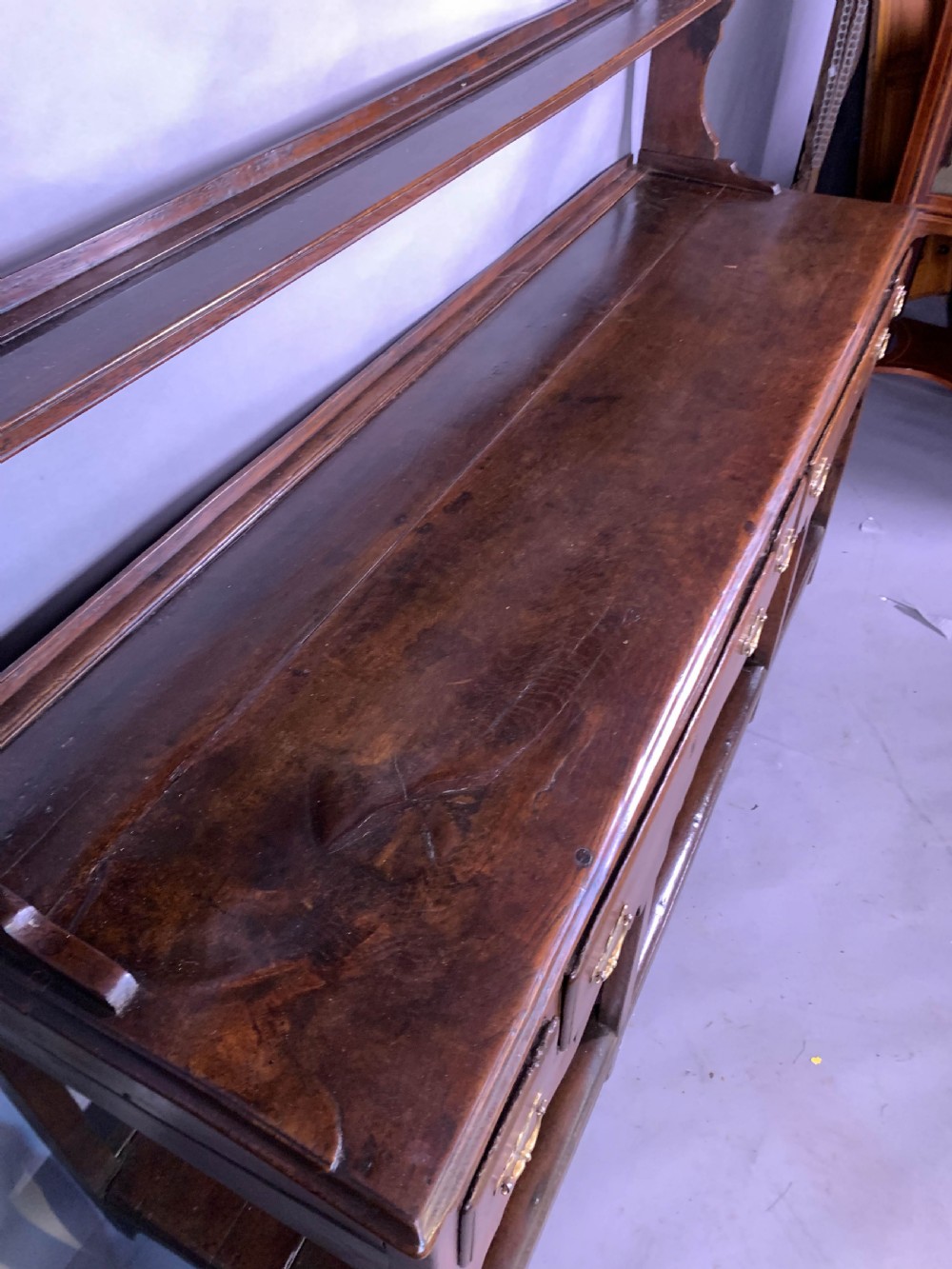 An 18th-century oak Welsh dresser featuring an open rack top with plate hooks, a central base with multiple drawers, and a lower pot board shelf. View XIII