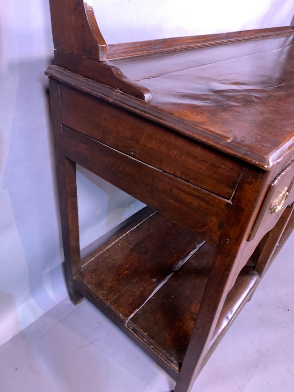 An 18th-century oak Welsh dresser featuring an open rack top with plate hooks, a central base with multiple drawers, and a lower pot board shelf. View XIV