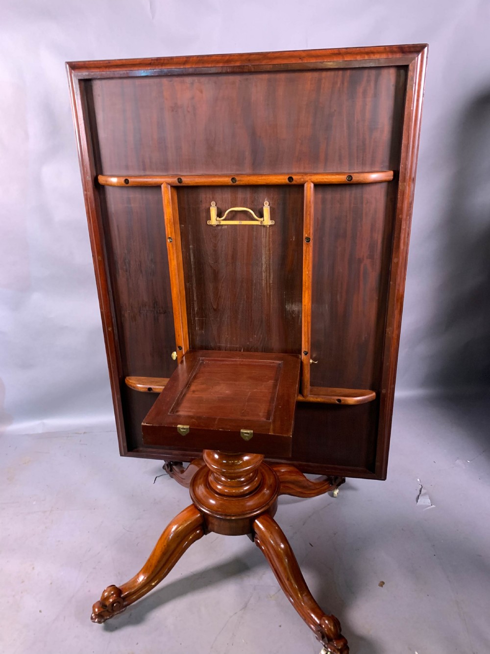 A rectangular mahogany breakfast dining table featuring a polished flame mahogany top set upon a central carved pedestal with splayed legs and brass castors. View VIII