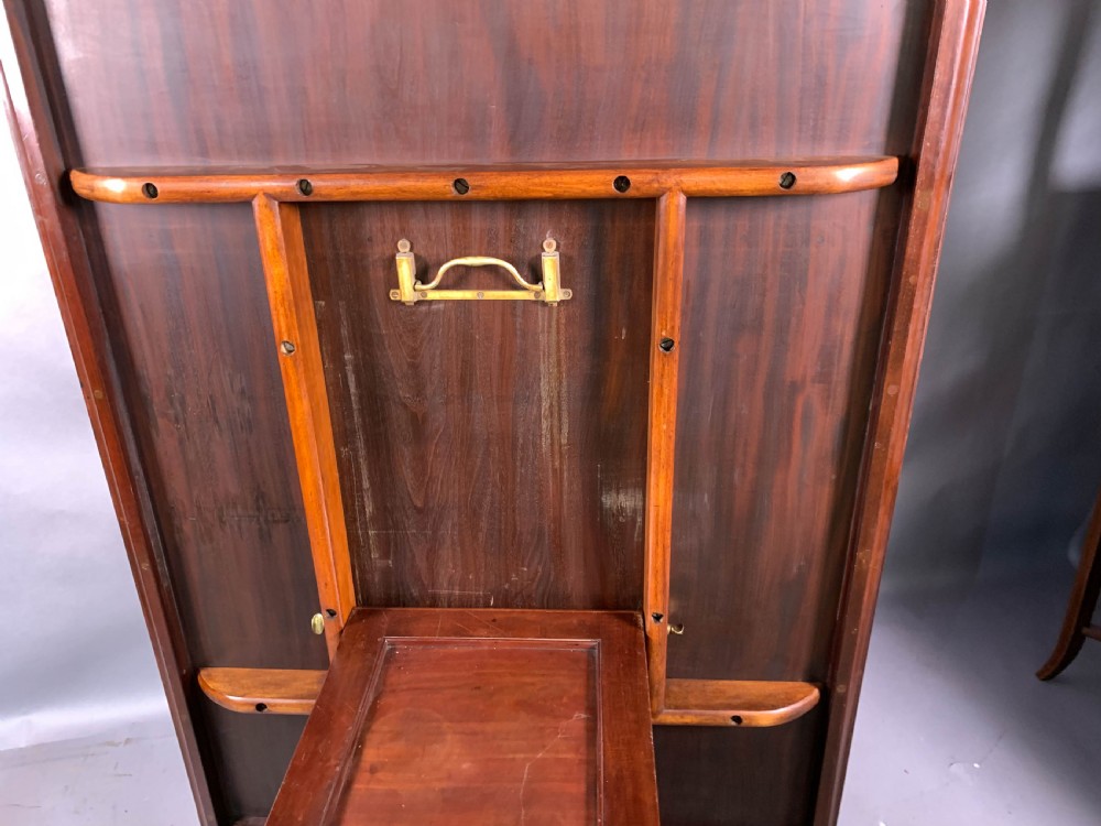 A rectangular mahogany breakfast dining table featuring a polished flame mahogany top set upon a central carved pedestal with splayed legs and brass castors. View IX