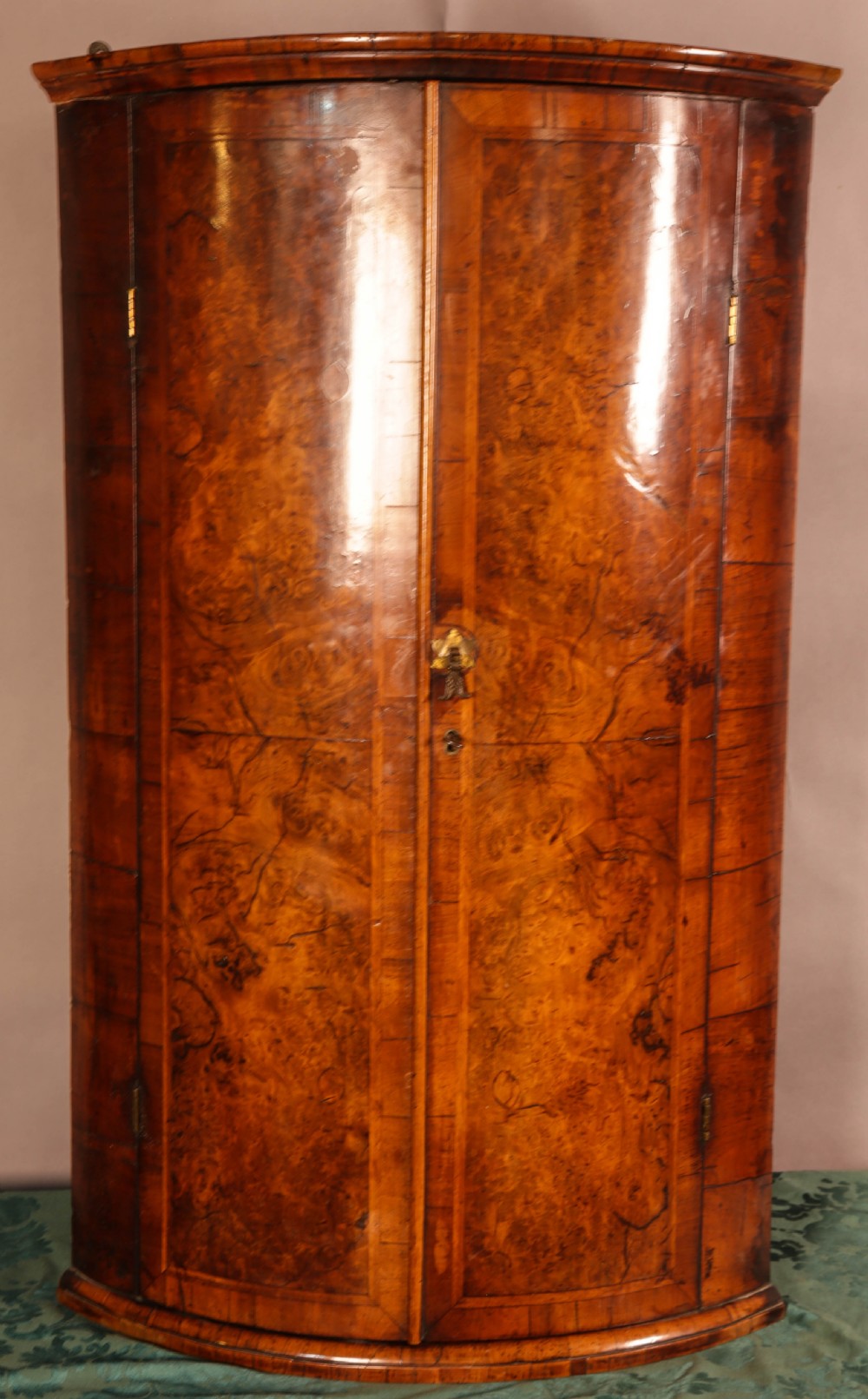 An eighteenth-century English bow-fronted corner cupboard crafted from figure-grained burr walnut with twin doors and a central brass escutcheon. View III