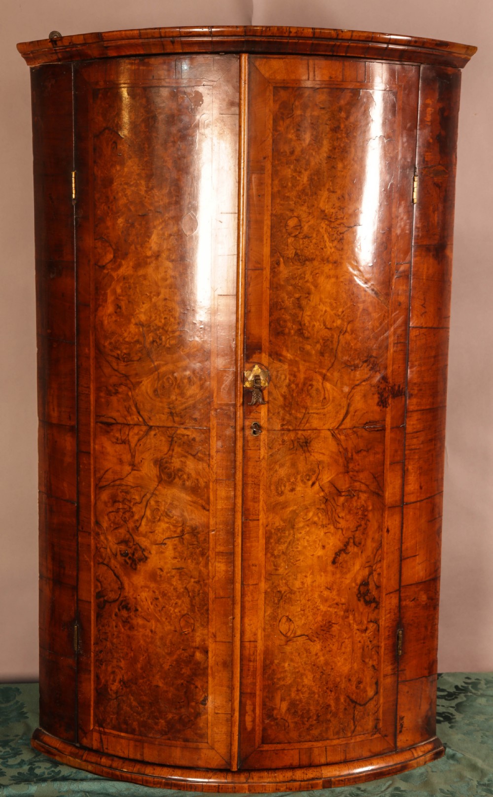 An eighteenth-century English bow-fronted corner cupboard crafted from figure-grained burr walnut with twin doors and a central brass escutcheon. View IV