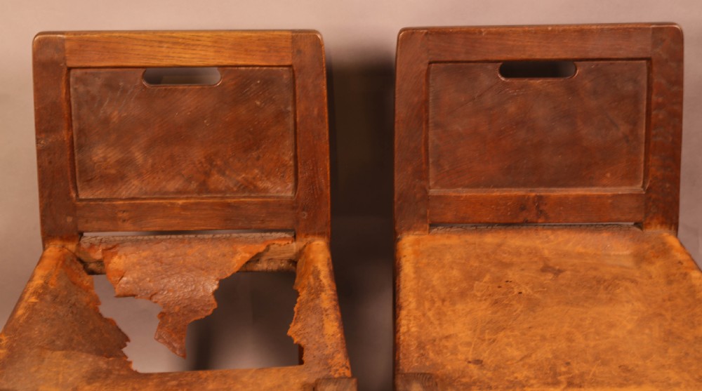 A pair of 1930s Arts and Crafts English oak side chairs featuring solid backs with cut-out handles, turned front legs with signature carved mouse motifs, and worn brown leather seats. View III