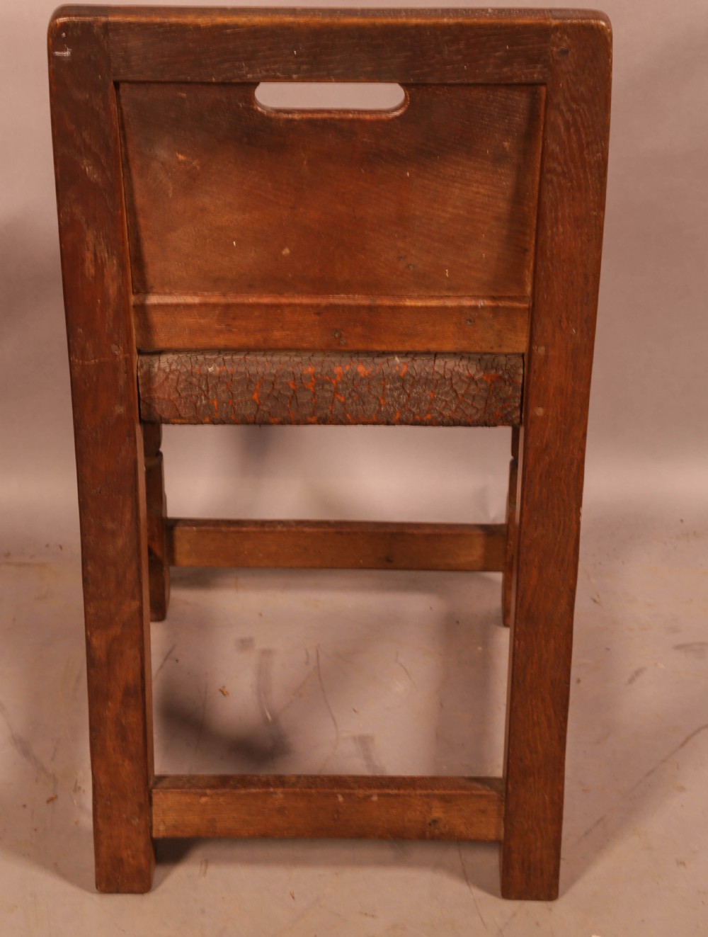 A pair of 1930s Arts and Crafts English oak side chairs featuring solid backs with cut-out handles, turned front legs with signature carved mouse motifs, and worn brown leather seats. View V