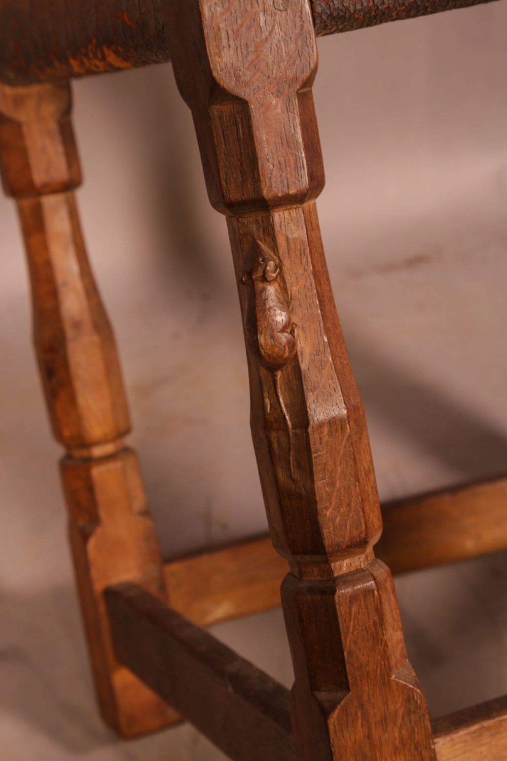 A pair of 1930s Arts and Crafts English oak side chairs featuring solid backs with cut-out handles, turned front legs with signature carved mouse motifs, and worn brown leather seats. View VI