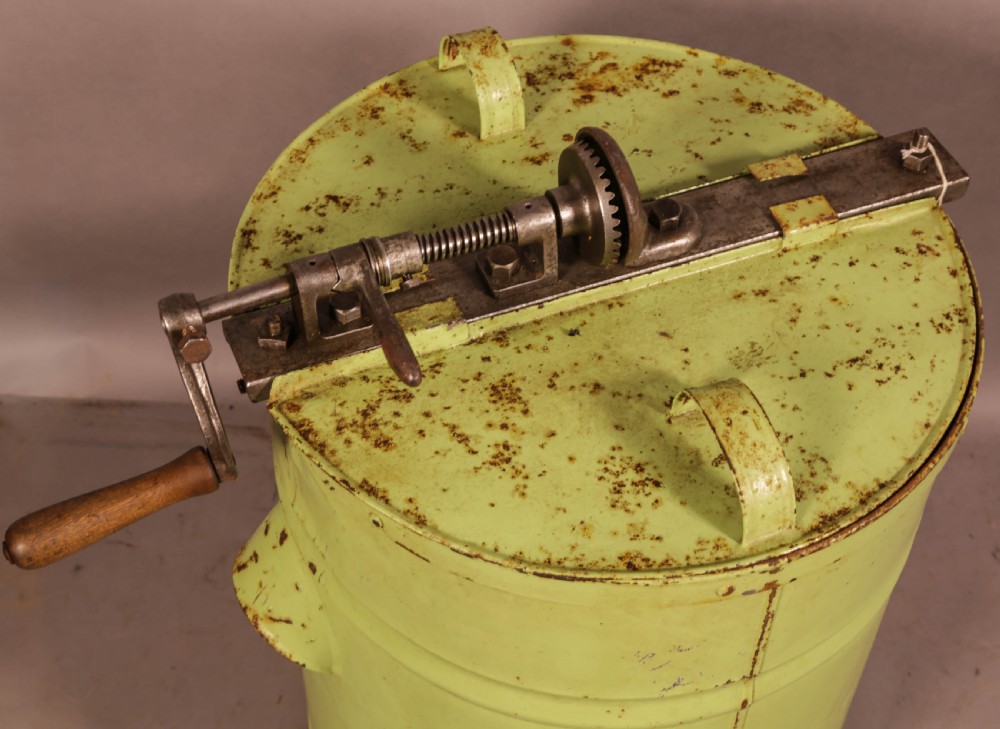 A pale green cylindrical metal honey separator with a top-mounted cast iron hand-crank mechanism and wooden handle. View II