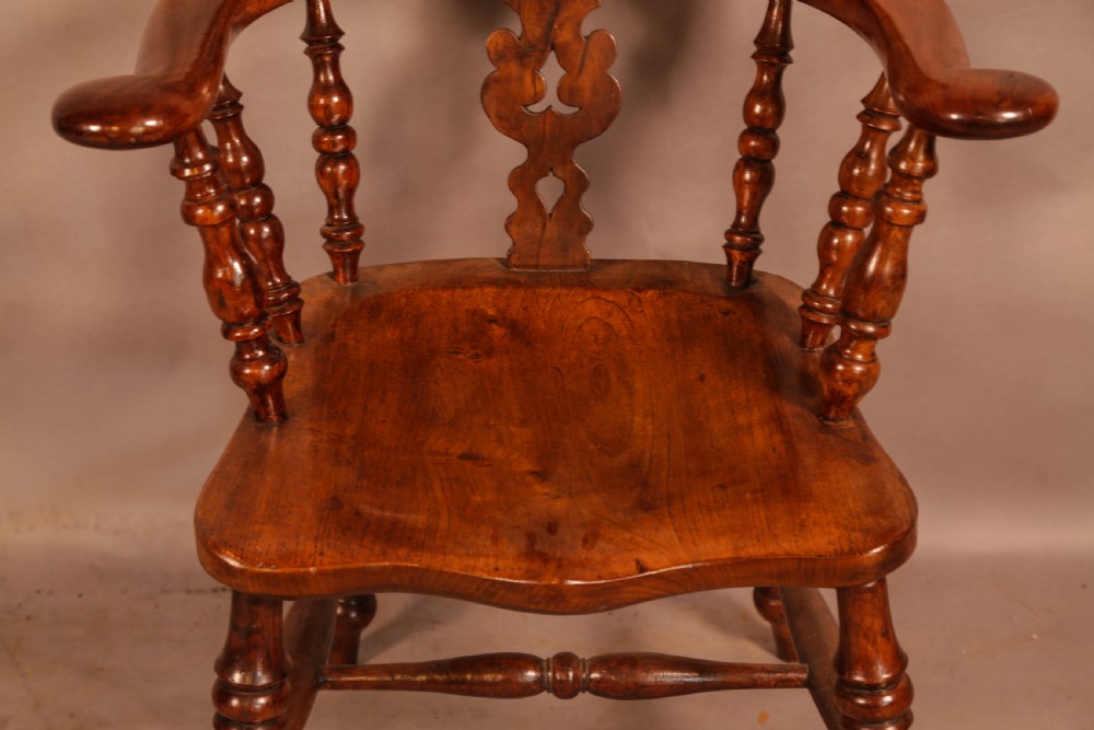 An antique yew wood Windsor armchair featuring a bowed hoop back, pierced splat, turned legs, and a solid elm seat. View V