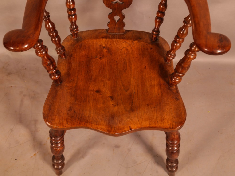 An antique yew wood Windsor armchair featuring a bowed hoop back, pierced splat, turned legs, and a solid elm seat. View X