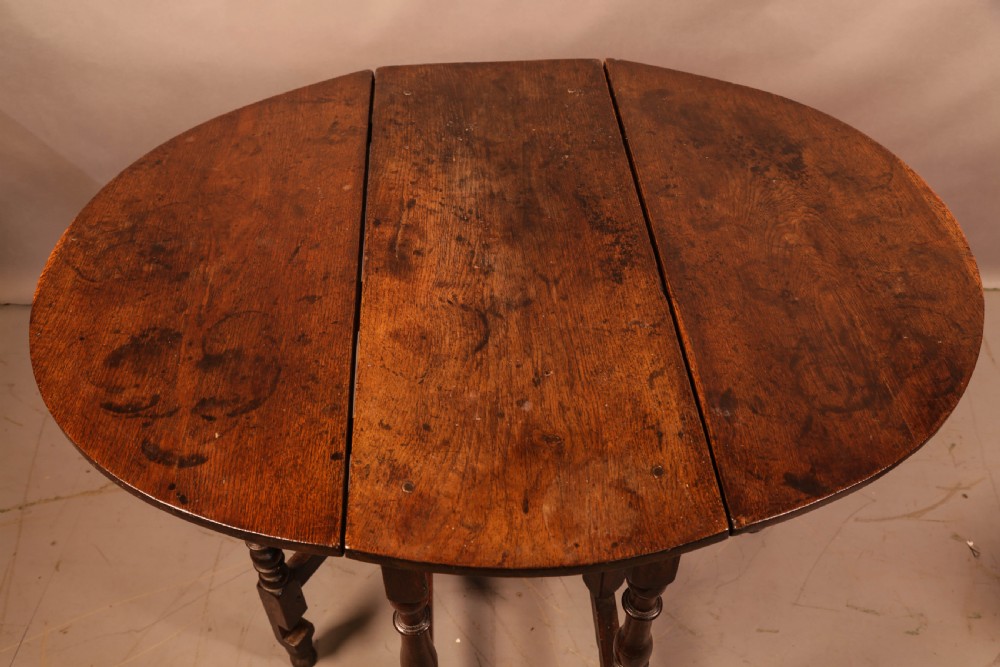 An antique dark oak gateleg table with turned legs and a drop-leaf oval top. View IV