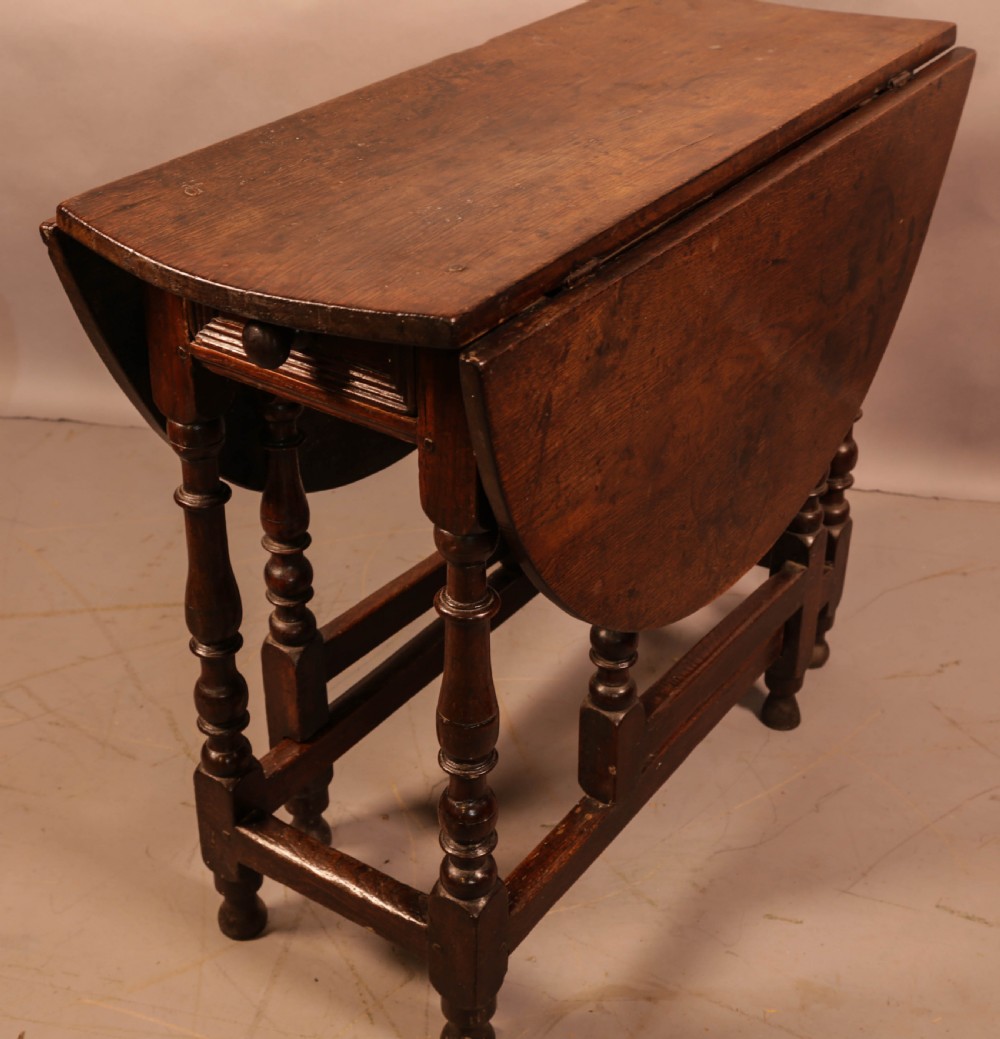 An antique dark oak gateleg table with turned legs and a drop-leaf oval top. View V