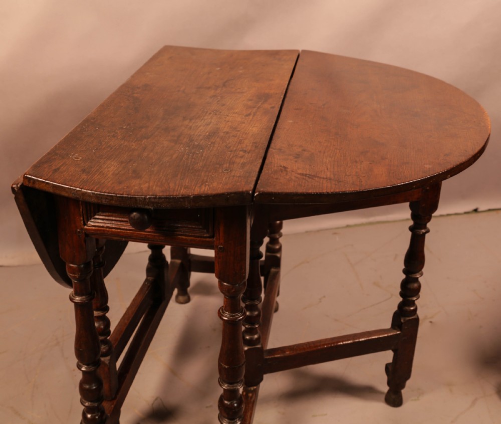 An antique dark oak gateleg table with turned legs and a drop-leaf oval top. View VII