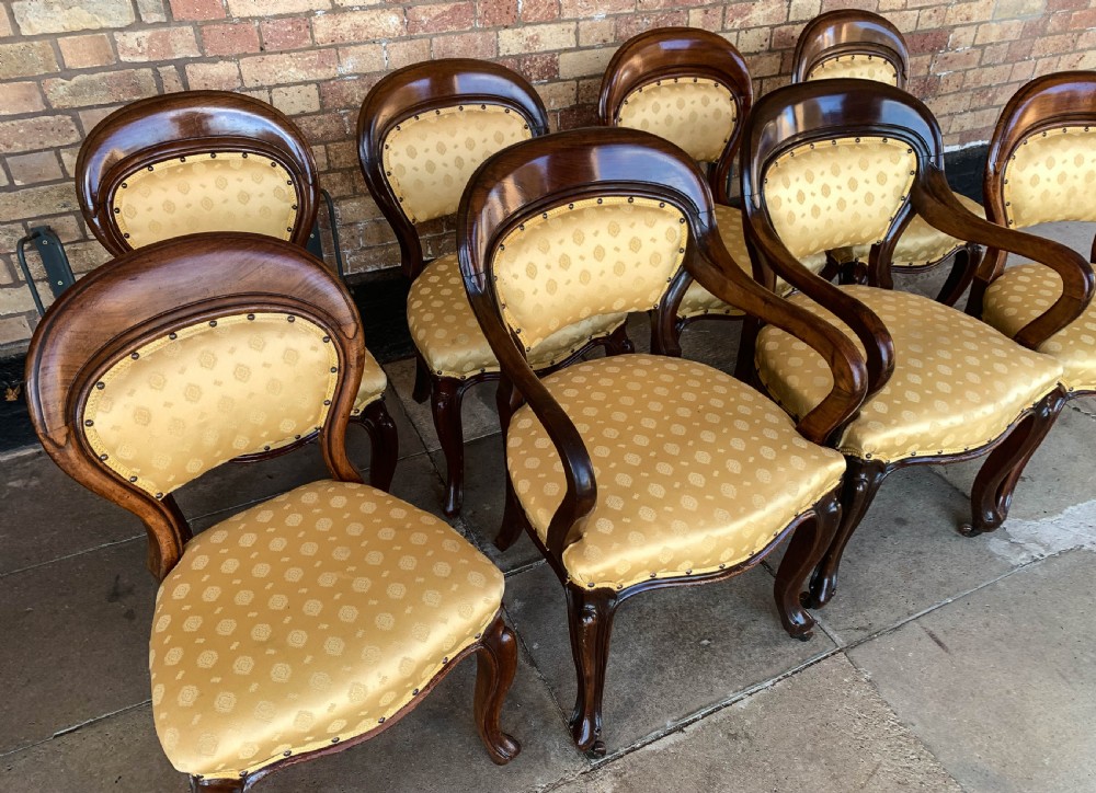 A set of eight Victorian mahogany dining chairs featuring gold patterned fabric upholstery, balloon backs, and cabriole legs. View V