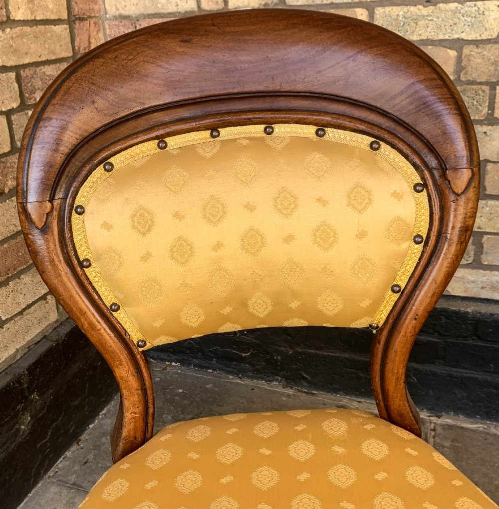 A set of eight Victorian mahogany dining chairs featuring gold patterned fabric upholstery, balloon backs, and cabriole legs. View VI