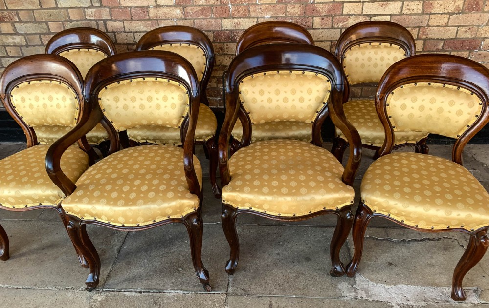 A set of eight Victorian mahogany dining chairs featuring gold patterned fabric upholstery, balloon backs, and cabriole legs. View XV