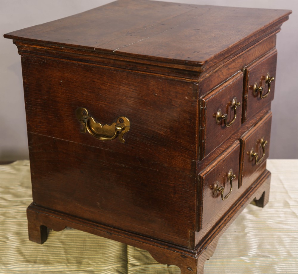 An 18th-century oak close stool designed with four faux drawer fronts, brass drop handles, and bracket feet. View II