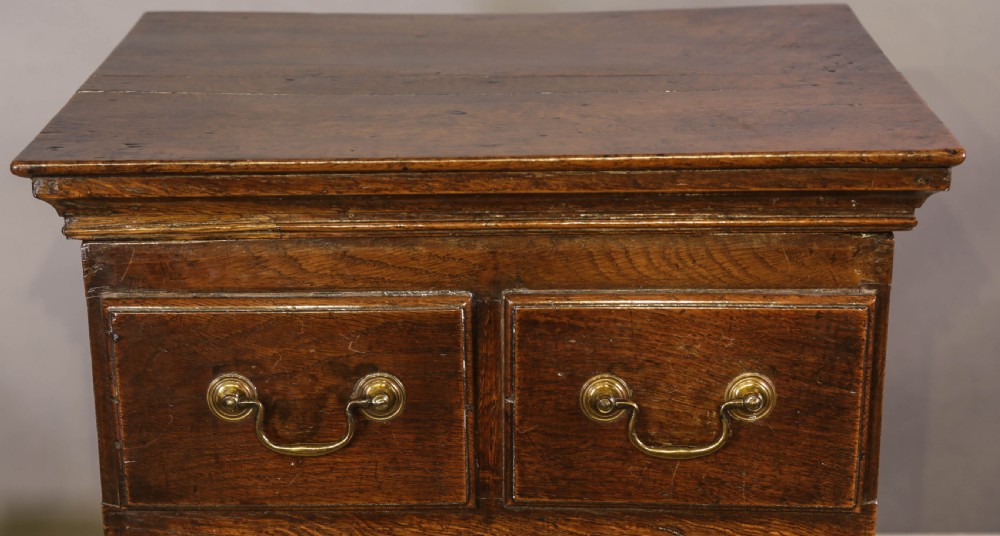 An 18th-century oak close stool designed with four faux drawer fronts, brass drop handles, and bracket feet. View III
