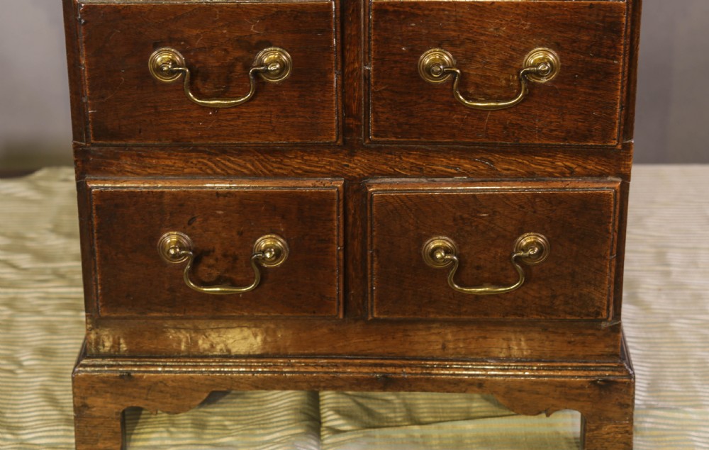 An 18th-century oak close stool designed with four faux drawer fronts, brass drop handles, and bracket feet. View IV
