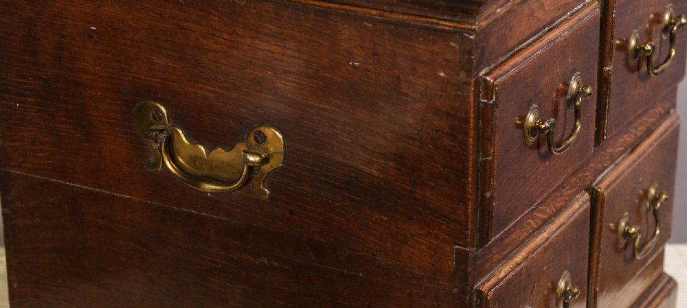 An 18th-century oak close stool designed with four faux drawer fronts, brass drop handles, and bracket feet. View VI