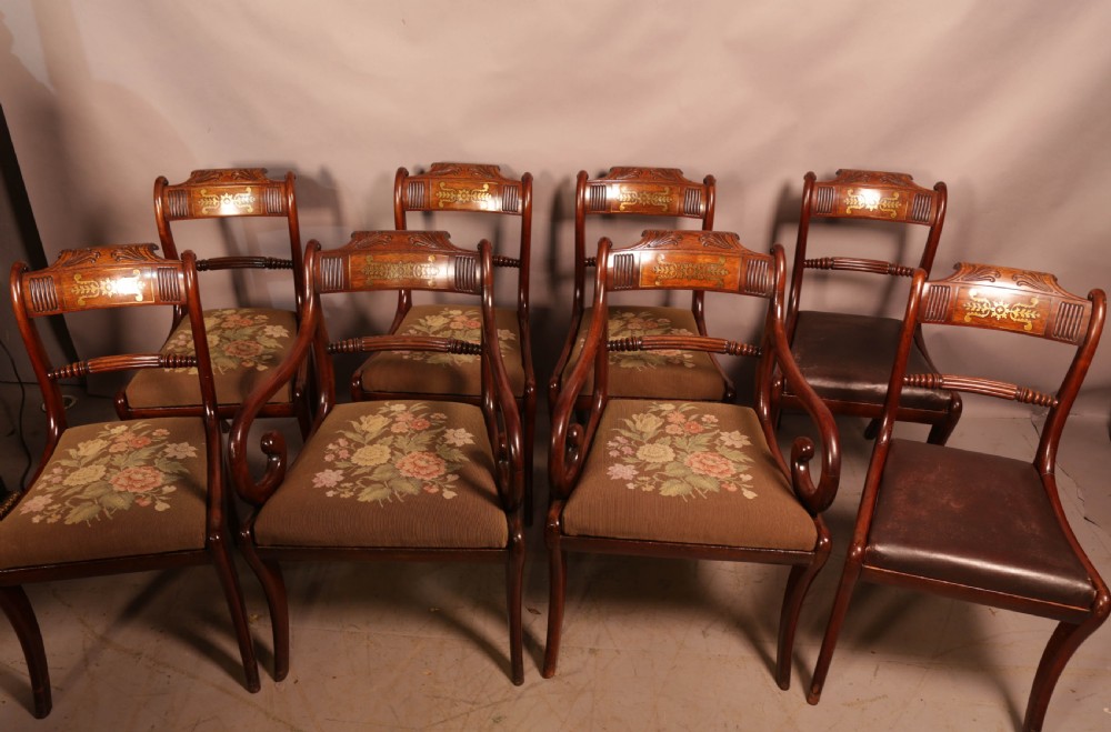 A matched set of eight Regency mahogany dining chairs featuring brass inlay on the top rails and upholstered seats.