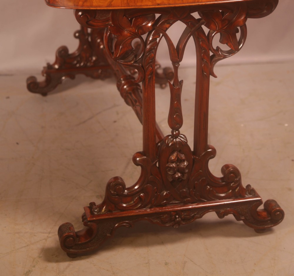 A Victorian burr walnut window table with a rectangular figured top, carved trestle supports, and a turned central stretcher. View VIII