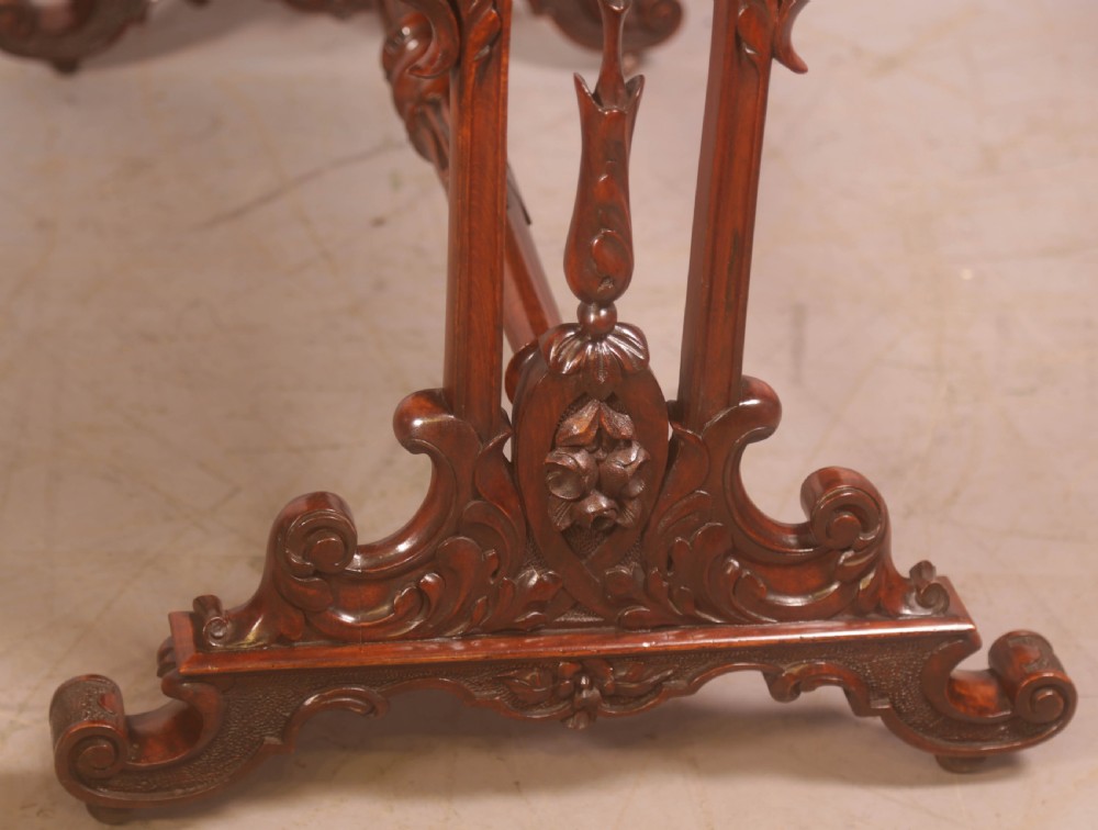 A Victorian burr walnut window table with a rectangular figured top, carved trestle supports, and a turned central stretcher. View IX