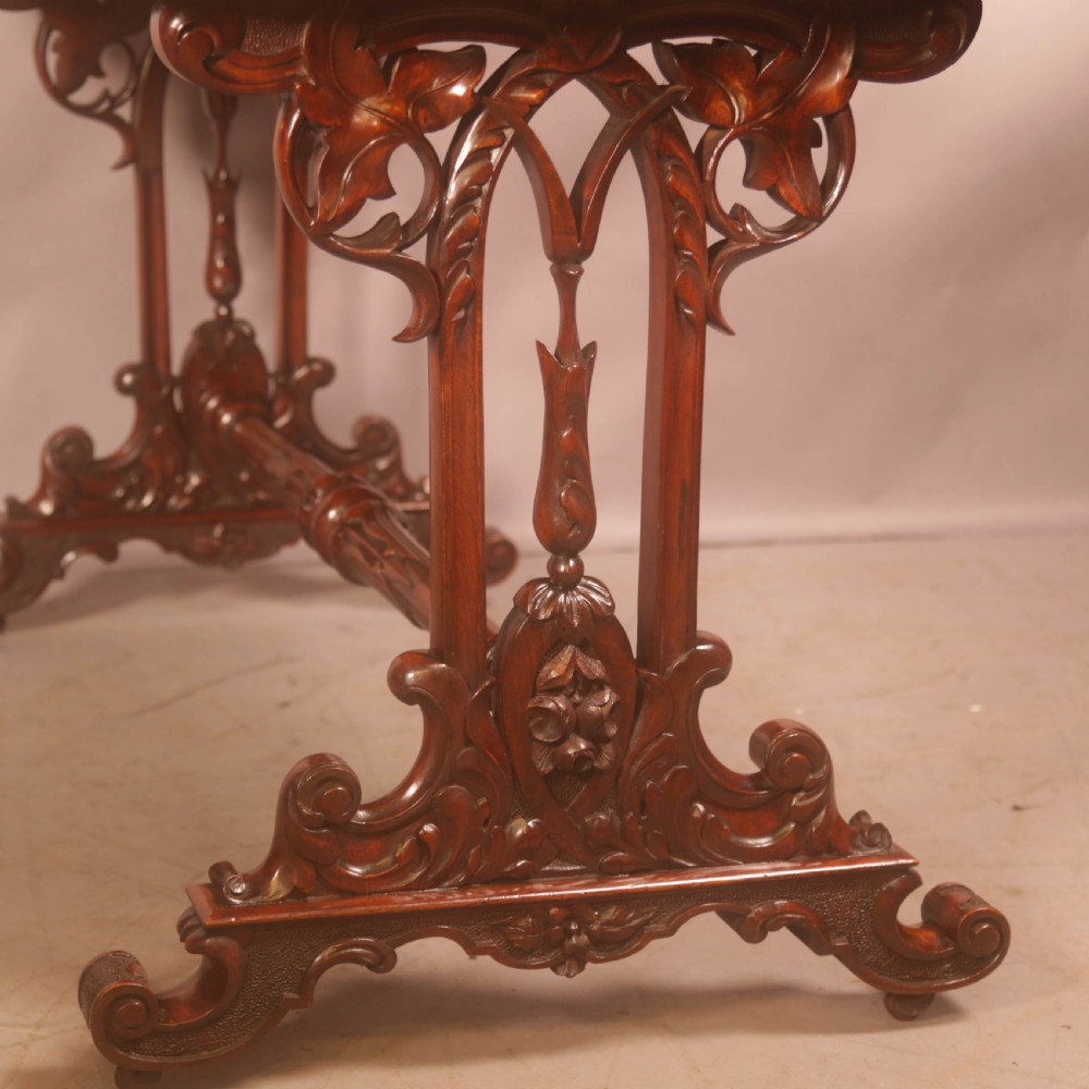 A Victorian burr walnut window table with a rectangular figured top, carved trestle supports, and a turned central stretcher. View XII