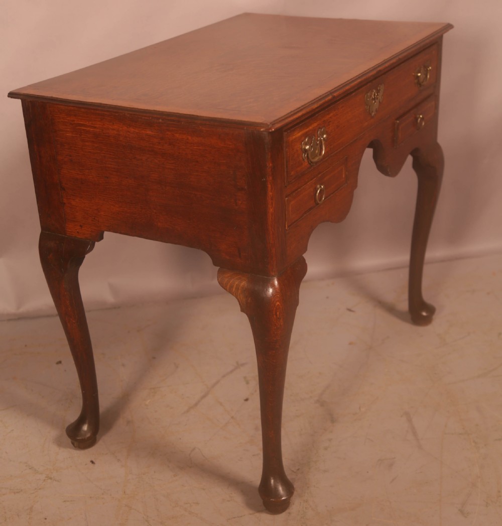 An eighteenth-century oak side table featuring a rectangular top, cabriole legs, and three drawers with brass drop handles. View VI