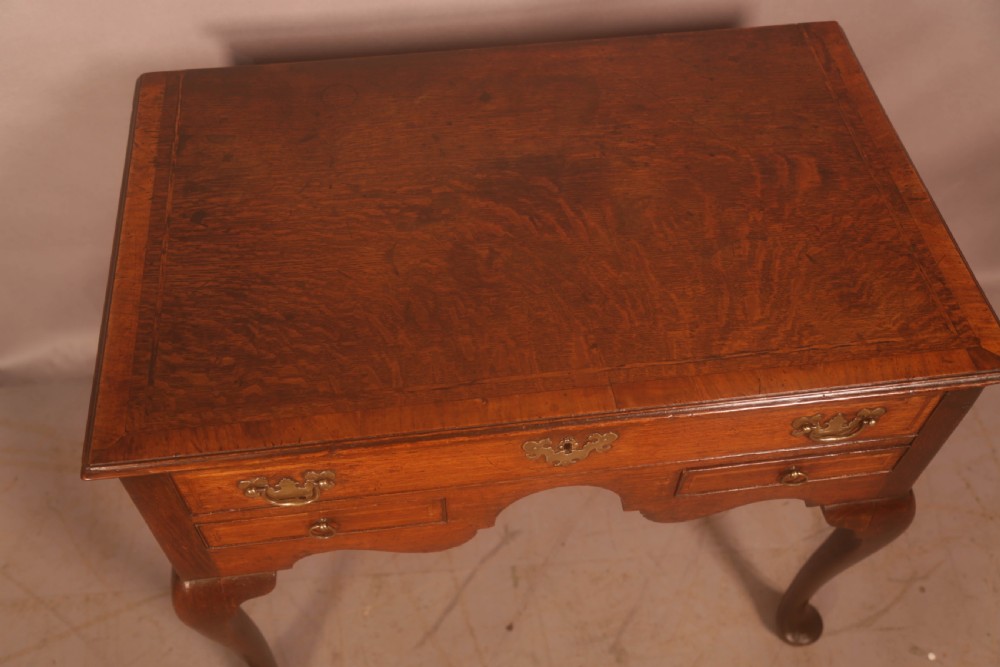An eighteenth-century oak side table featuring a rectangular top, cabriole legs, and three drawers with brass drop handles. View VII
