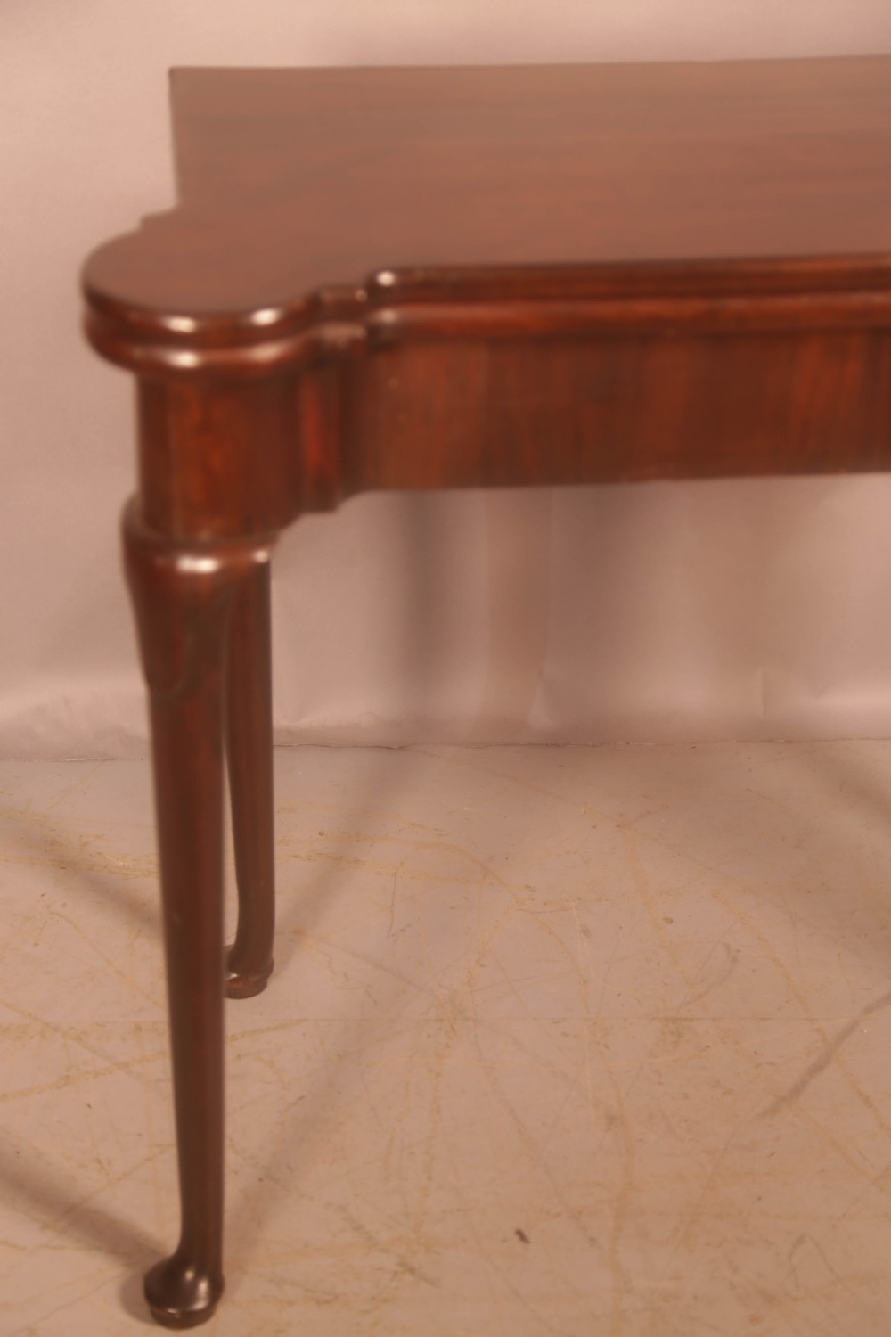 A mid-18th century Georgian mahogany fold-over card table featuring projecting rounded corners, a smooth apron, and slender cabriole legs terminating in pad feet. View IV