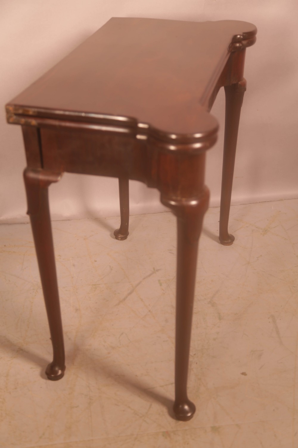 A mid-18th century Georgian mahogany fold-over card table featuring projecting rounded corners, a smooth apron, and slender cabriole legs terminating in pad feet. View V