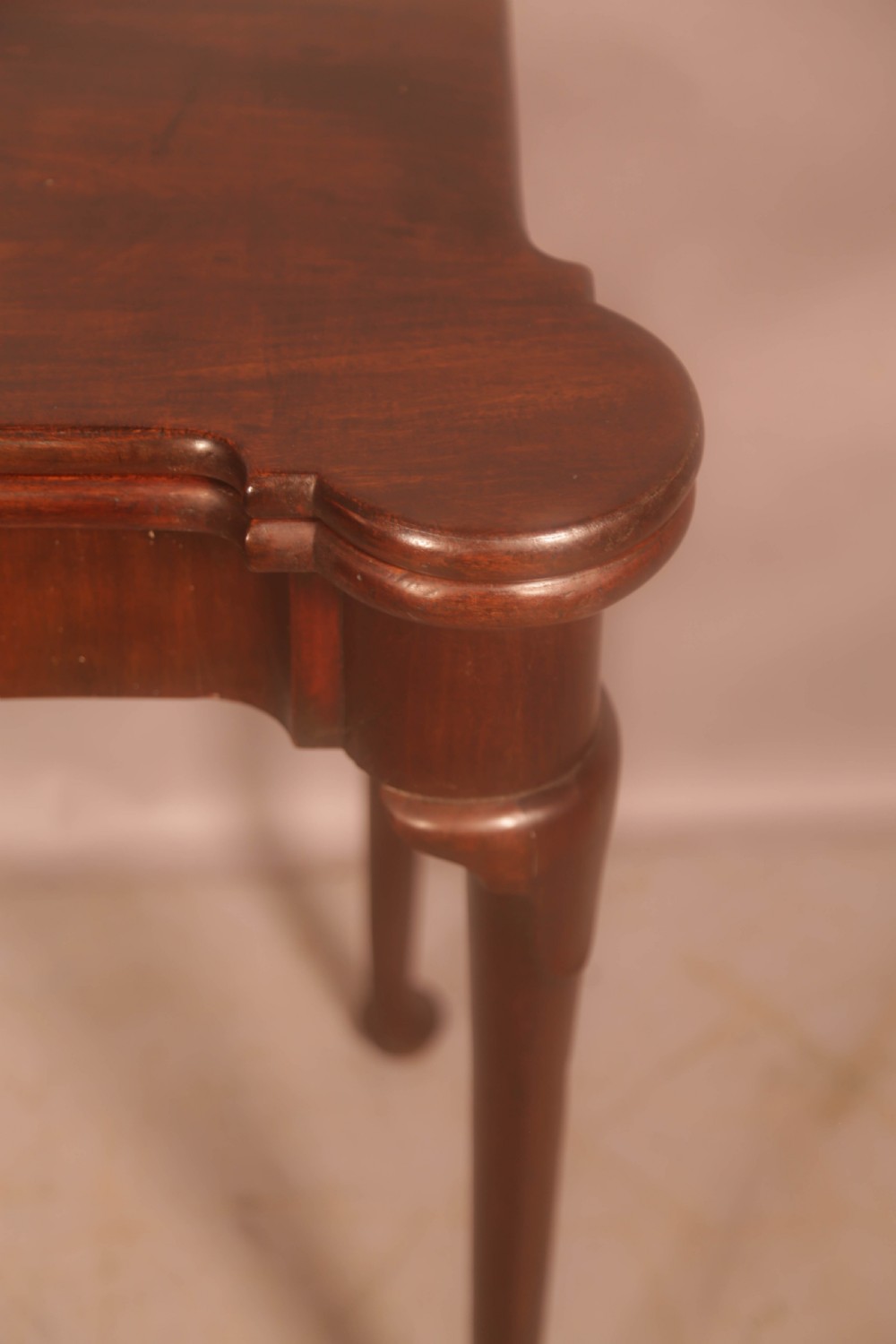 A mid-18th century Georgian mahogany fold-over card table featuring projecting rounded corners, a smooth apron, and slender cabriole legs terminating in pad feet. View XII