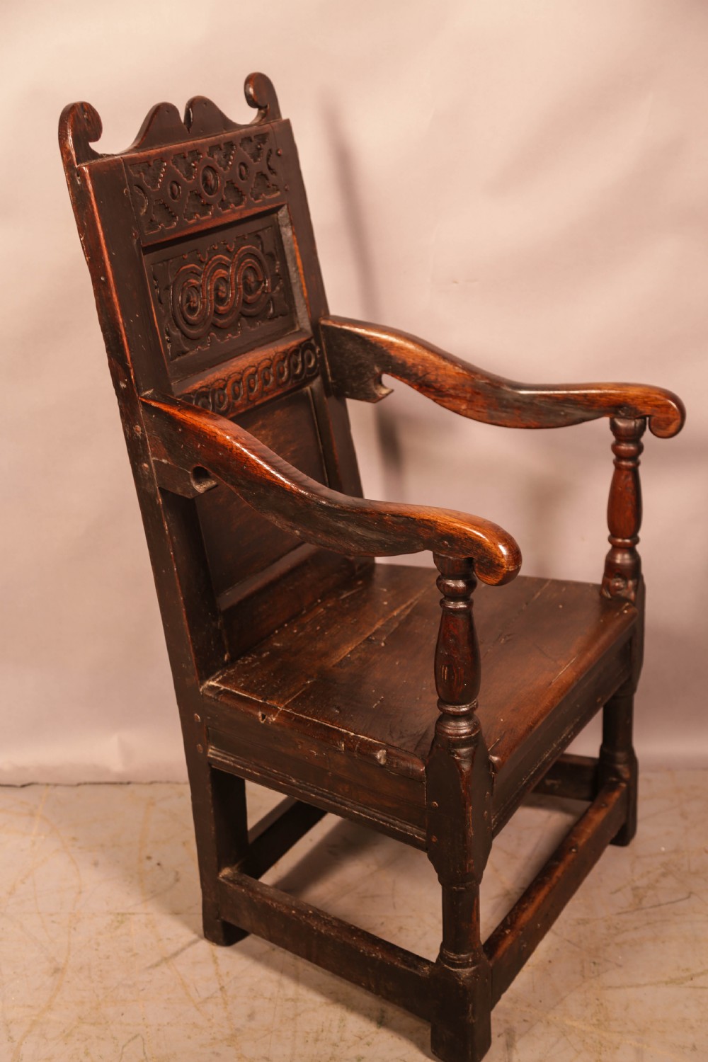 A dark oak 17th-century wainscot armchair with a carved panelled backrest, turned supports, and a solid wooden seat. View II