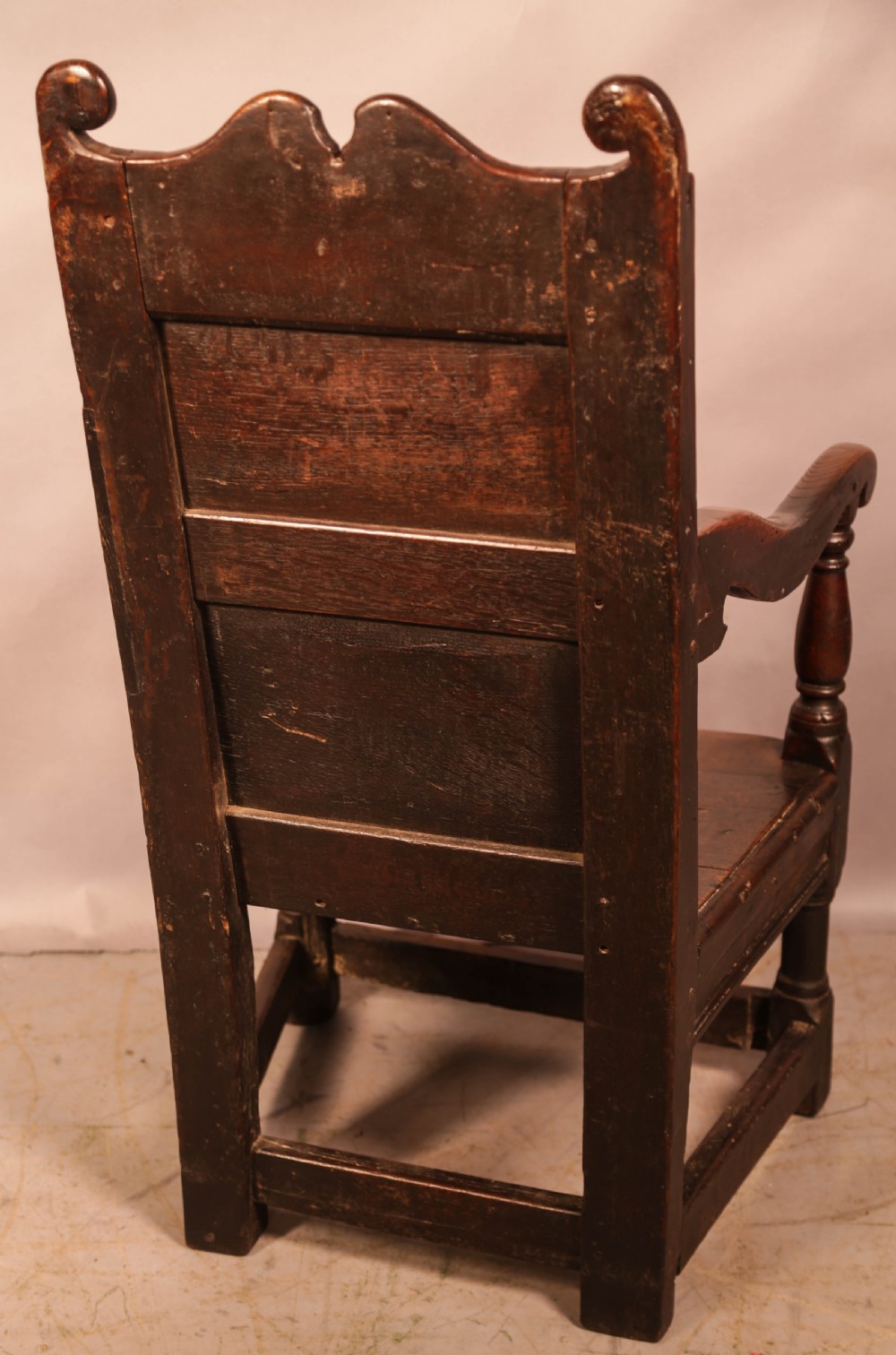 A dark oak 17th-century wainscot armchair with a carved panelled backrest, turned supports, and a solid wooden seat. View III