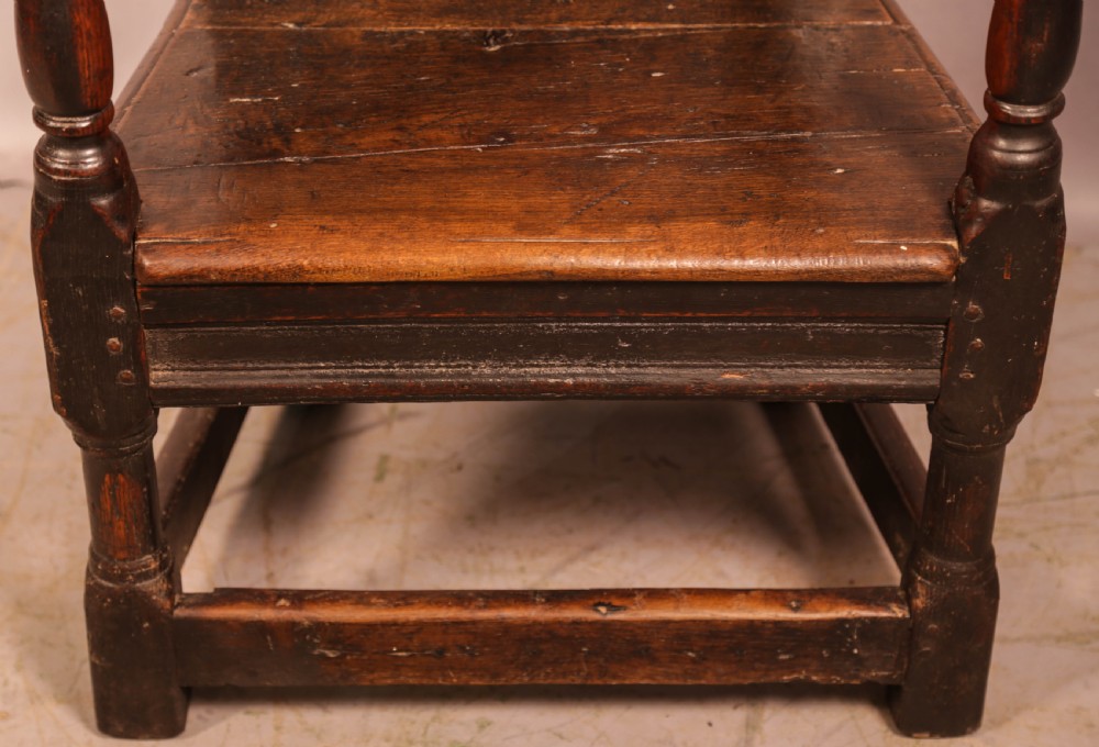 A dark oak 17th-century wainscot armchair with a carved panelled backrest, turned supports, and a solid wooden seat. View IV
