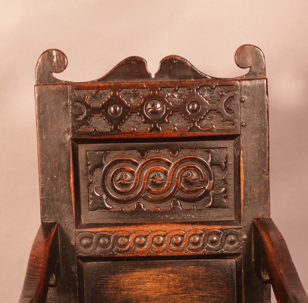 A dark oak 17th-century wainscot armchair with a carved panelled backrest, turned supports, and a solid wooden seat. View VI