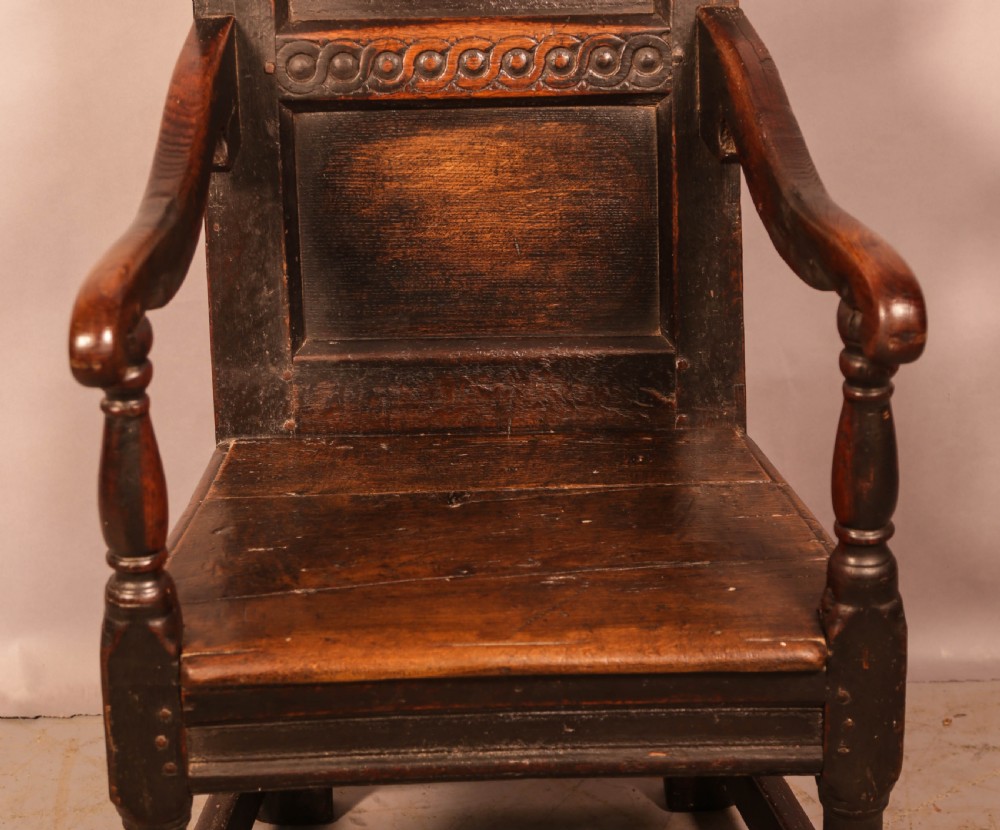 A dark oak 17th-century wainscot armchair with a carved panelled backrest, turned supports, and a solid wooden seat. View VIII