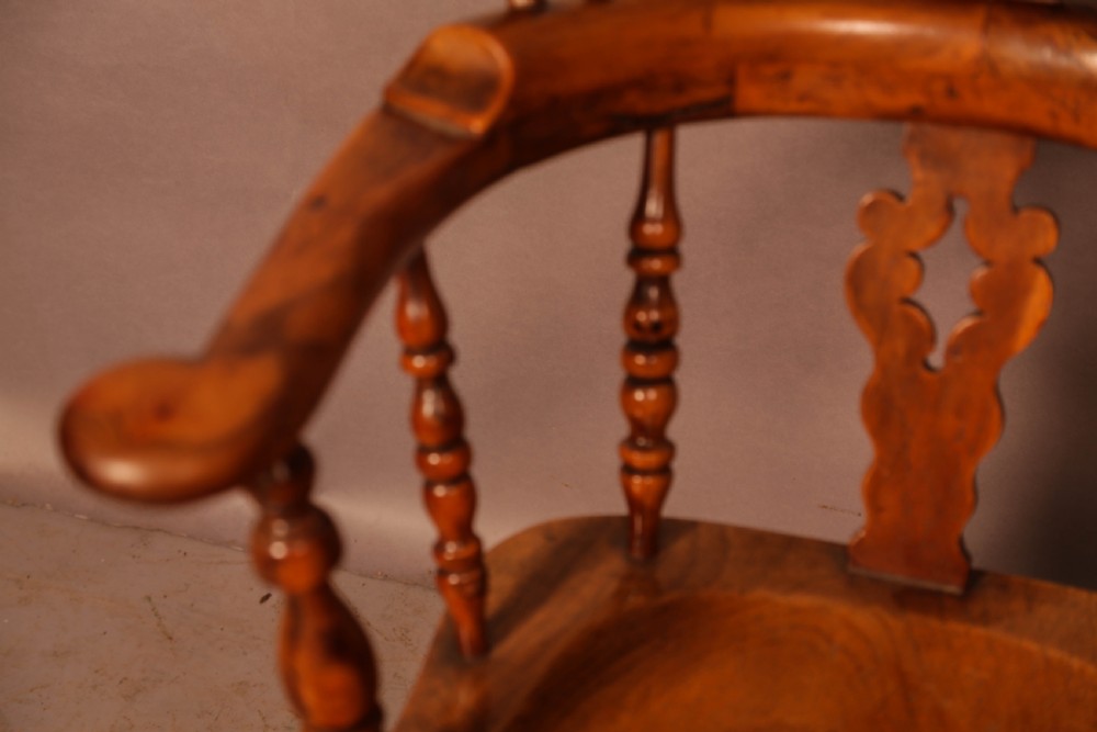 An antique English yew wood broad arm Windsor chair featuring a hooped back with a central pierced splat, turned legs, and a solid wood saddle seat. View VI