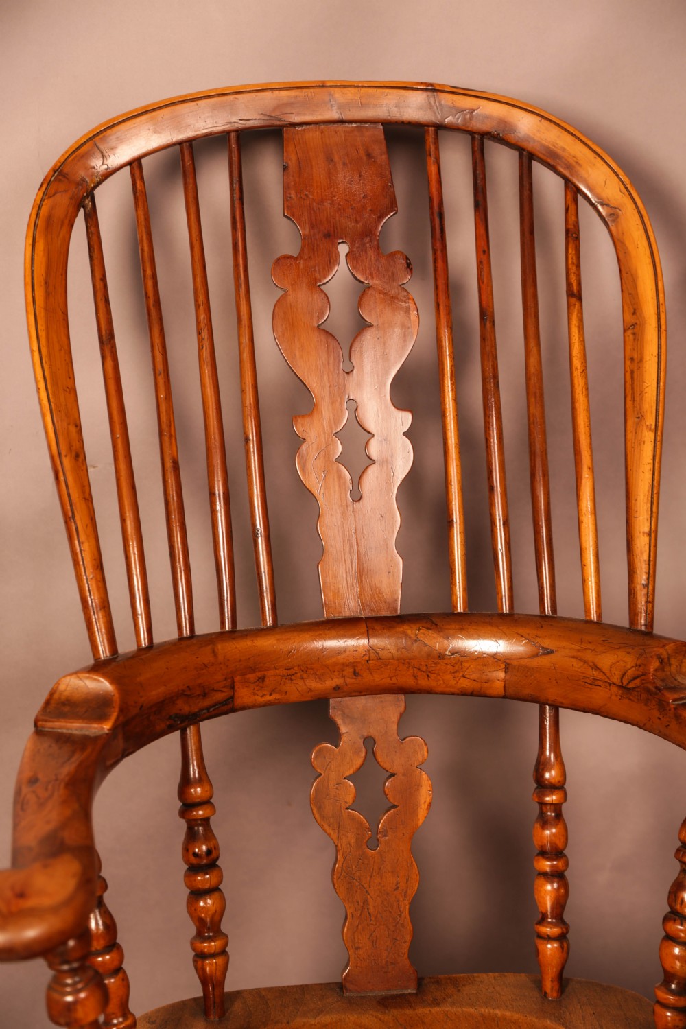 An antique English yew wood broad arm Windsor chair featuring a hooped back with a central pierced splat, turned legs, and a solid wood saddle seat. View IX