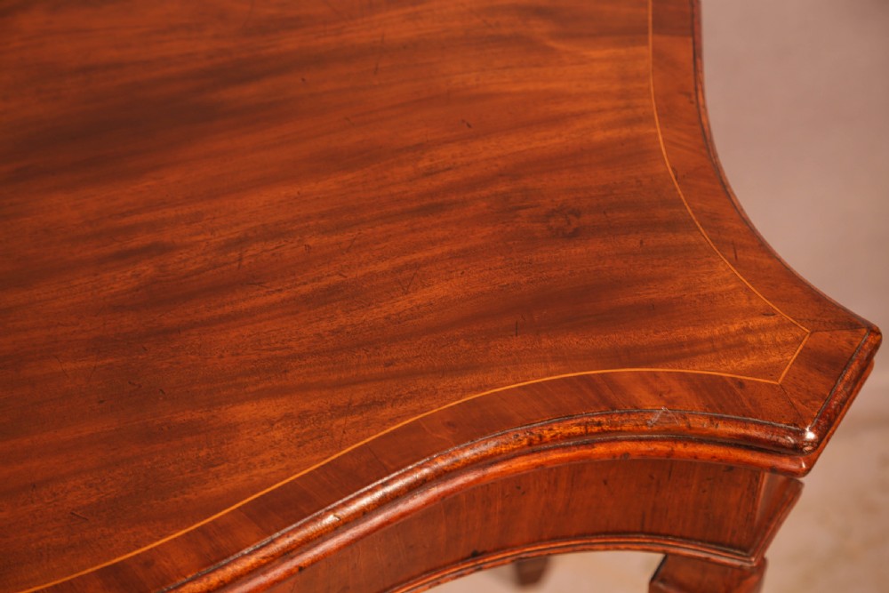 An 18th-century Georgian mahogany games table featuring a serpentine-curved folding top and fluted tapered legs. View IV