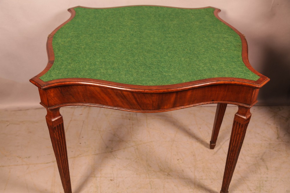 An 18th-century Georgian mahogany games table featuring a serpentine-curved folding top and fluted tapered legs. View VI