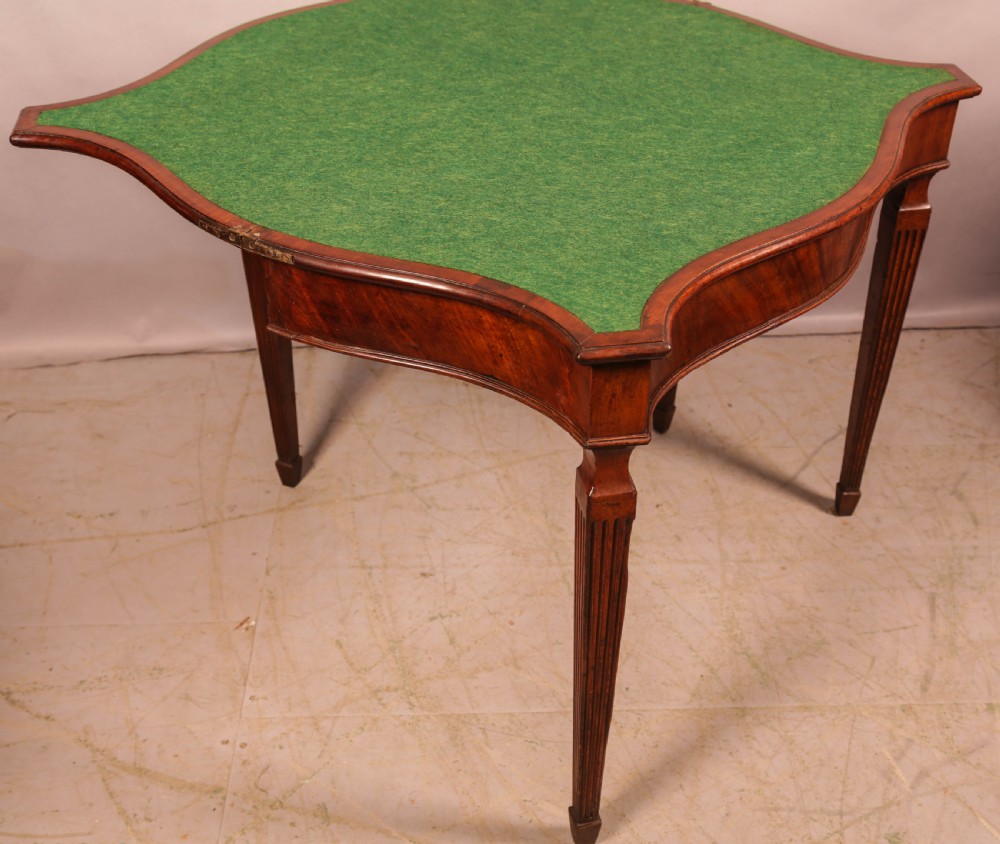 An 18th-century Georgian mahogany games table featuring a serpentine-curved folding top and fluted tapered legs. View VII