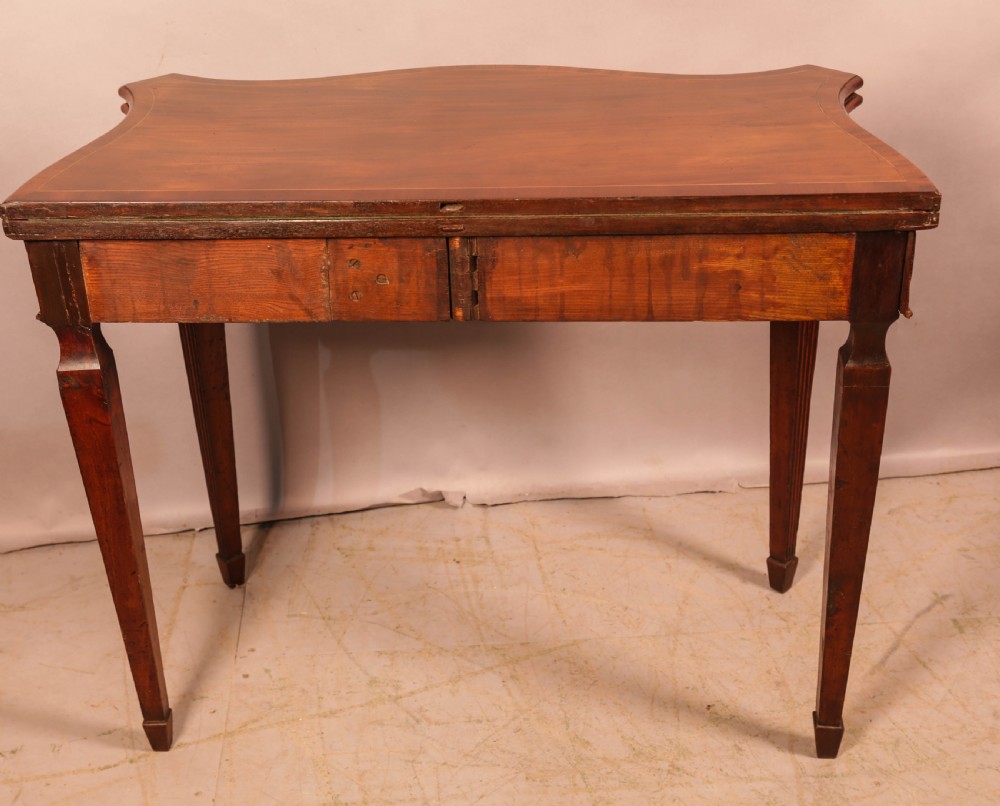 An 18th-century Georgian mahogany games table featuring a serpentine-curved folding top and fluted tapered legs. View IX
