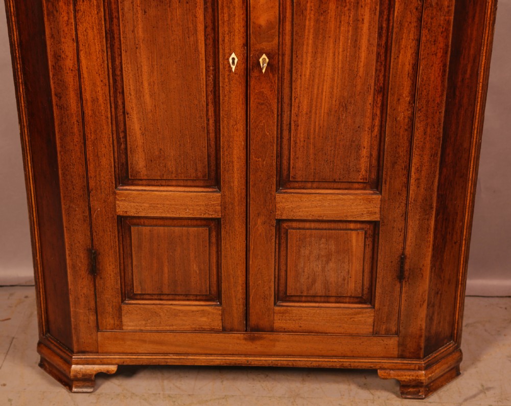 An 18th-century freestanding mahogany corner cupboard featuring arched double panel doors, keyhole escutcheons, and bracket feet. View IV