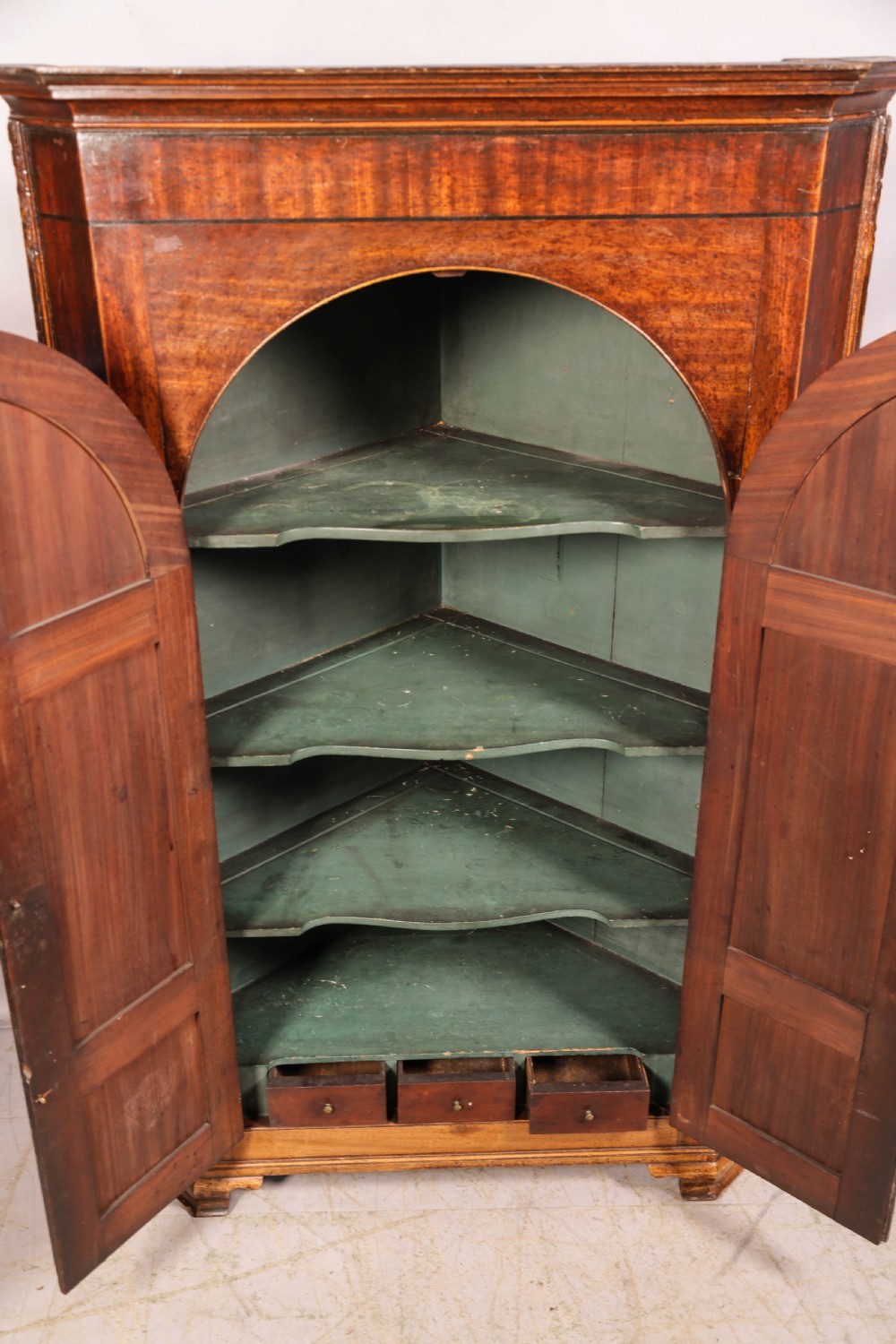 An 18th-century freestanding mahogany corner cupboard featuring arched double panel doors, keyhole escutcheons, and bracket feet. View VIII
