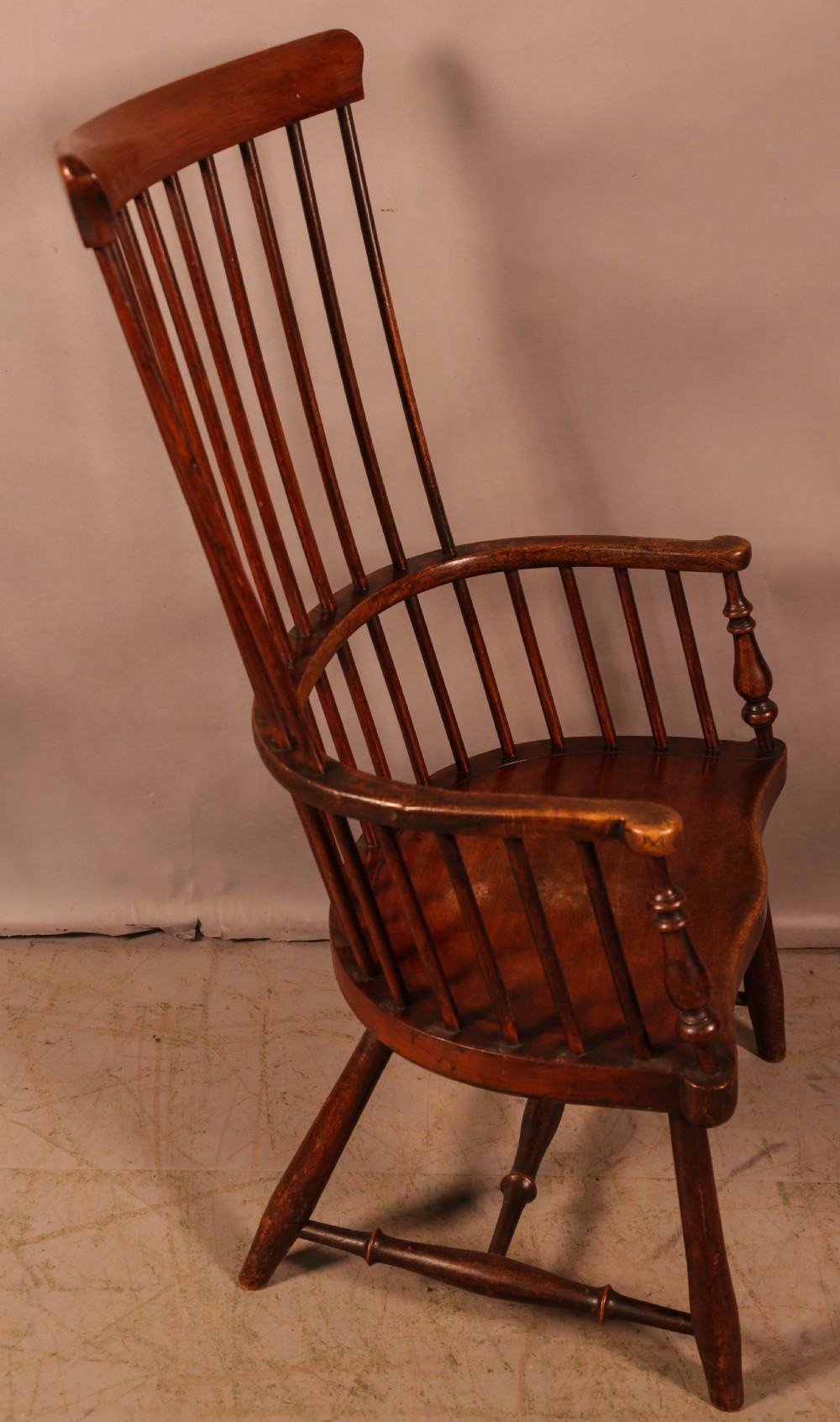 A high-back Scottish Darvel Windsor armchair crafted from warm brown wood, featuring a comb crest rail, spindle back, curved arm bow, and saddle seat. View II