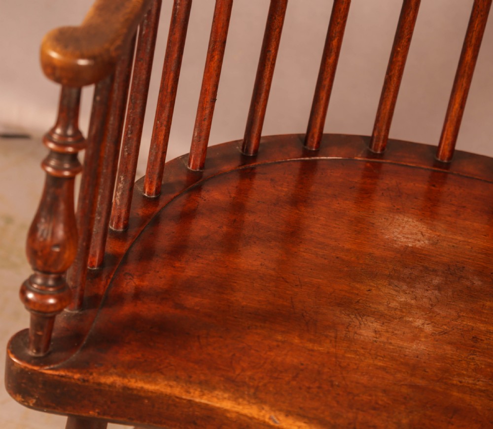 A high-back Scottish Darvel Windsor armchair crafted from warm brown wood, featuring a comb crest rail, spindle back, curved arm bow, and saddle seat. View IV