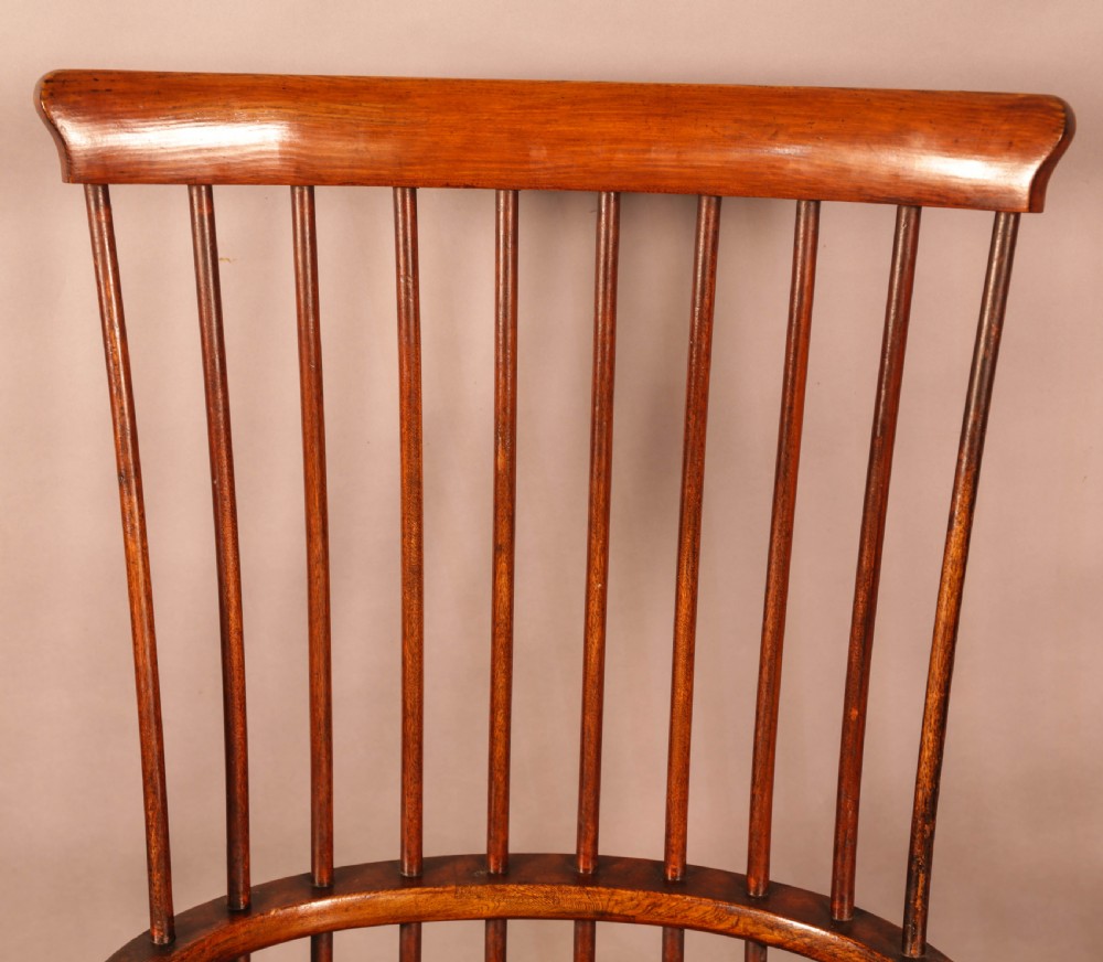 A high-back Scottish Darvel Windsor armchair crafted from warm brown wood, featuring a comb crest rail, spindle back, curved arm bow, and saddle seat. View VII