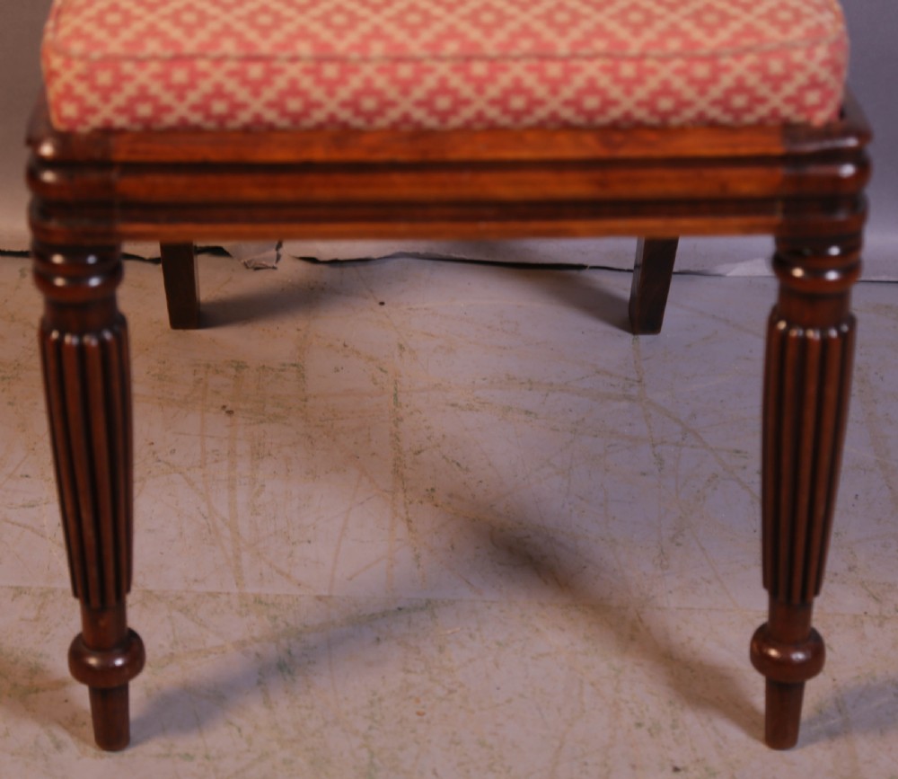 A set of four Regency rosewood dining chairs featuring brass inlay on the curved crest rails, carved splats, reeded front legs, and patterned red seats. View IV
