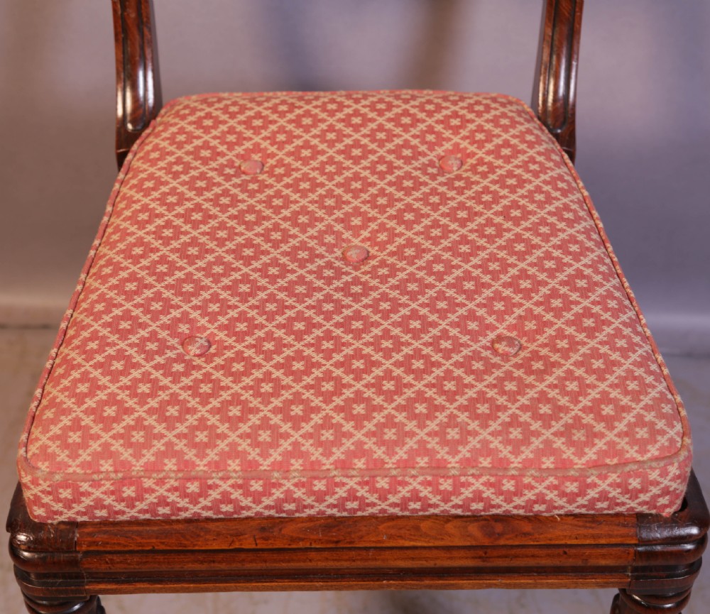 A set of four Regency rosewood dining chairs featuring brass inlay on the curved crest rails, carved splats, reeded front legs, and patterned red seats. View VIII